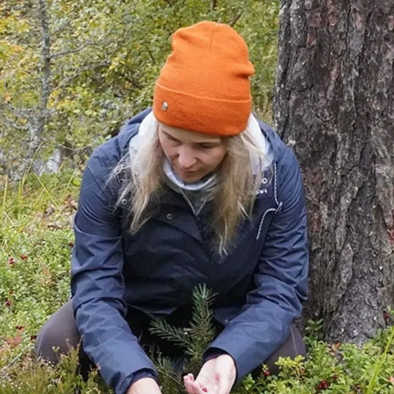 Katja poimii puolukoita metsässä merinovillapipo päässä